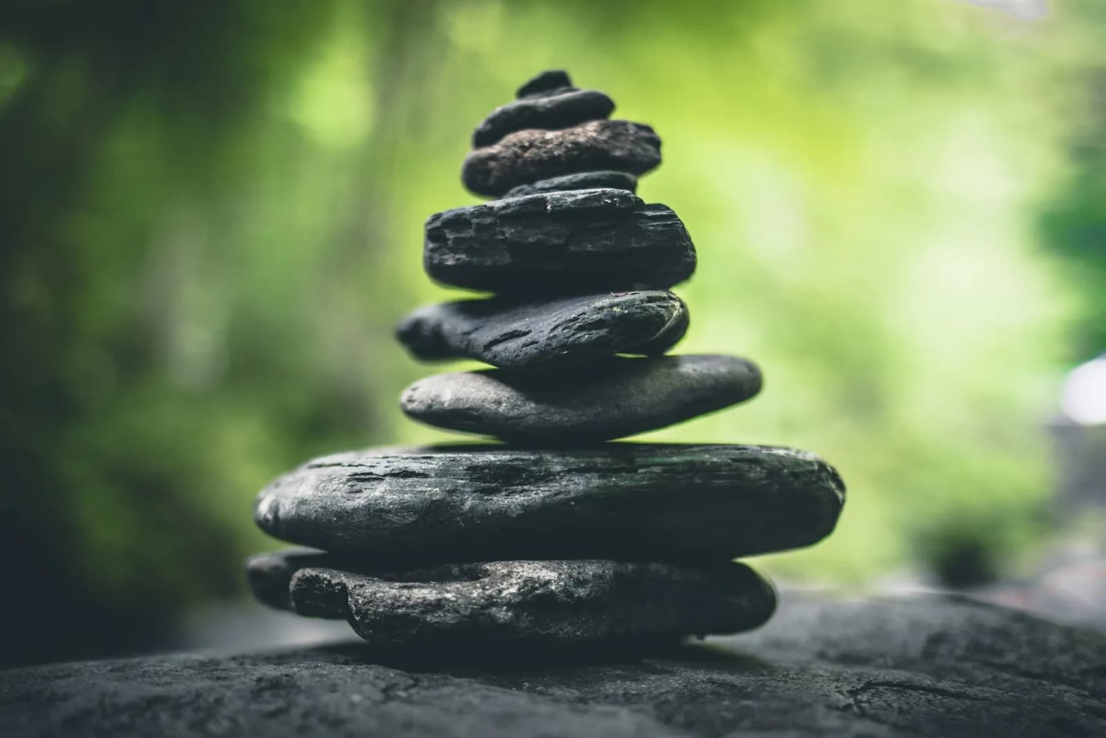 Three smooth stones stacked in a sunlit natural setting